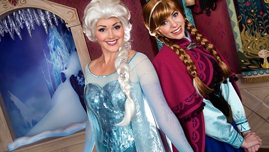 Elsa and Anna greet fans with sparkling smiles in a wintry, Frozen-themed Disney World room, enchanting guests of all ages.