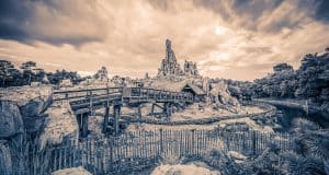 Sepia photo of Big Thunder Mountain Railroad at Walt Disney World, showcasing its iconic rugged peaks and wooden trestle bridge.
