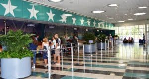 Disney fans line up in a lively, star-adorned lobby at a Value Resort, sunlight streaming through big windows for an energetic welcome.