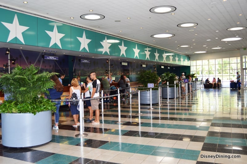Disney fans line up in a lively, star-adorned lobby at a Value Resort, sunlight streaming through big windows for an energetic welcome.