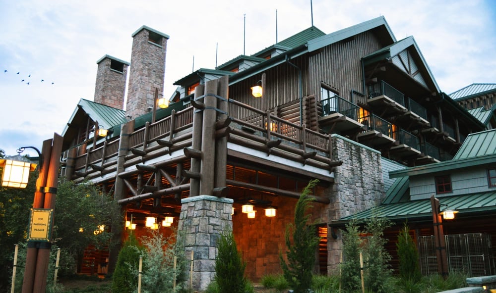 Wilderness Lodge Resort at Disney World glows at dusk, with stone pillars, wood beams, green roofs—inviting a truly magical stay.