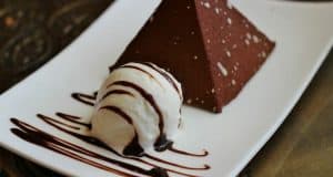 Chocolate pyramid dessert at Disney World, topped with rich sauce and vanilla ice cream, served on a sleek white plate.
