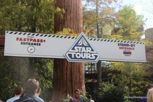 Star Tours – The Adventures Continue entrance with FastPass+ and Stand-By lanes, bustling guests, and lush greenery at Disney's Hollywood Studios.