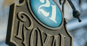 21 Royal’s elegant sign welcomes guests at Disneyland, crowned with a blue oval “21”—your gateway to an exclusive dining adventure.
