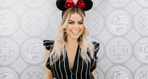 Disney Springs guest, sporting Minnie Mouse ears and a chic black-striped outfit, poses by a vibrant patterned wall.
