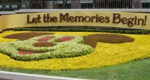 Mickey Mouse-shaped flower bed with a "Let the Memories Begin!" sign welcomes guests to Disney World magic.