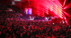 Excited fans cheer as their favorite band rocks the stage with dazzling red and purple lights at Night of Joy in Disney World.