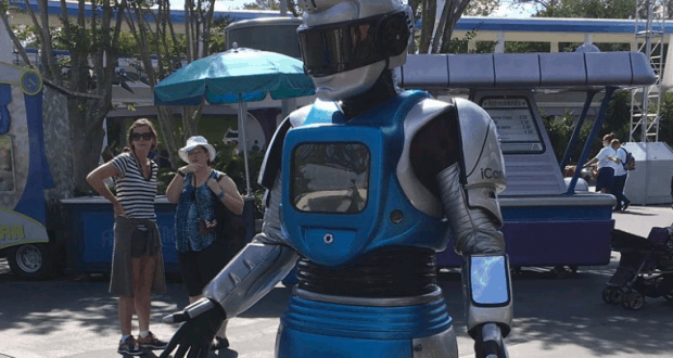 ICan the Robot delights guests outside among lively vendor booths, its silver and blue suit gleaming at the festival.