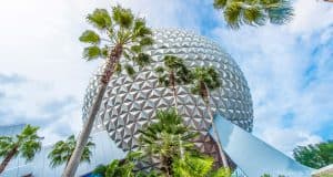 Spaceship Earth at Epcot rises above palm trees under a partly cloudy sky, capturing the magic of Walt Disney World adventure.