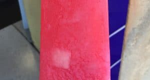 Enjoy a vibrant pink popsicle on a stick, perfect for cooling off between attractions at the theme park, near tiled decor.