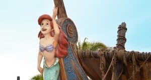 Ariel, the Little Mermaid, perched on a ship’s prow, delights Magic Kingdom guests beneath the iconic Florida sunshine.