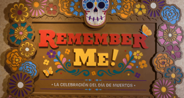 Vibrant Día de Muertos sign with colorful flowers and sugar skull, reads “Remember Me!” at Epcot in Walt Disney World.