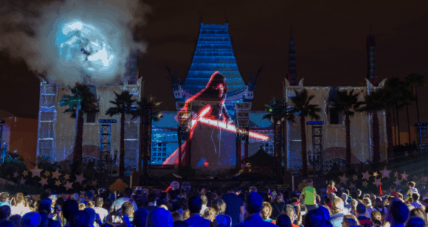 Guests gather at Disney’s Star Wars: Galactic Nights as a red lightsaber lights up the night with dazzling building projections.