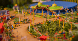 Toy Story Land-inspired miniature amusement park with a twisting model roller coaster amid vibrant greenery and playful decor.