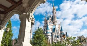 Cinderella Castle at Magic Kingdom, surrounded by lush trees and columns beneath a bright blue sky—pure Disney magic awaits.