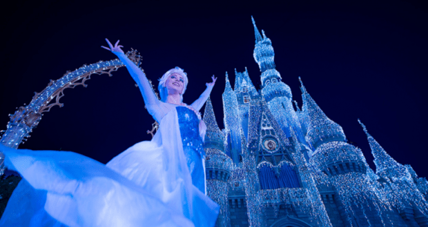 Elsa dazzles guests with raised arms before the sparkling, ice-covered Cinderella Castle during Walt Disney World's Frozen show.