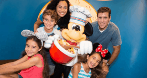 Smiling family with Mickey Mouse at Disney World, girls in mouse ears, captured by PhotoPass for a magical memory.