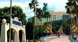 Walk across a palm-lined bridge to the vibrant Swan & Dolphin Resort at Disney World, crowned by iconic rooftop swans.