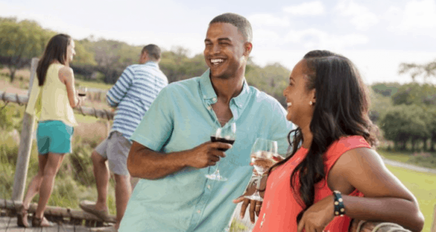 Guests raising wine glasses and laughing during a Savor the Savanna adventure at Disney’s Animal Kingdom, others chatting nearby.