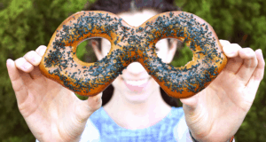 A guest delights in a sprinkle-covered pretzel, showcasing Tomorrowland Expo’s playful snacks at Walt Disney World.