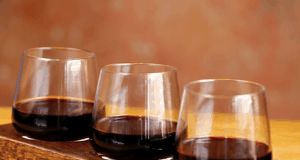 Trio of red wines on a wooden tray at Maria & Enzo's in Disney Springs, set on a rustic table—cheers to National Wine Day!.