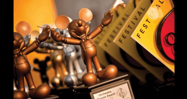 A gleaming bronze Mickey Mouse Orchestra Bronze Award shines beside bright yellow Festival Disney 2019 certificates.
