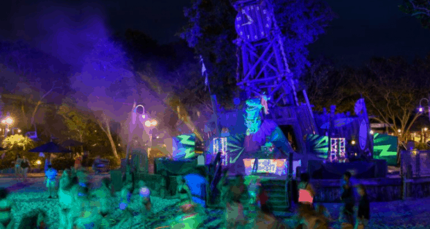 Guests dancing under neon lights at a vibrant beach party, with a DJ booth and dazzling colors—pure Disney World nightlife magic.