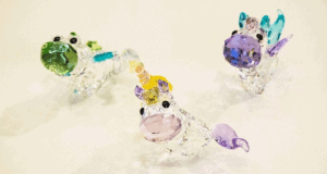 Three vibrant crystal unicorn figurines sparkle on white, capturing the enchanting fantasy of Disney Park souvenirs.