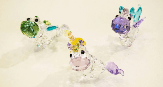 Three vibrant crystal unicorn figurines sparkle on white, capturing the enchanting fantasy of Disney Park souvenirs.