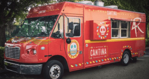 The Cantina food truck, decked out in red with festive skulls, serves barbacoa beneath the trees at Disney Springs.
