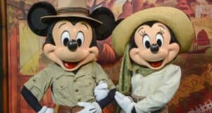 Two cartoon mice characters dressed in safari outfits. The one on the left wears a hat and khaki shirt, while the one on the right wears a large hat and scarf. They pose cheerfully against a themed backdrop.
