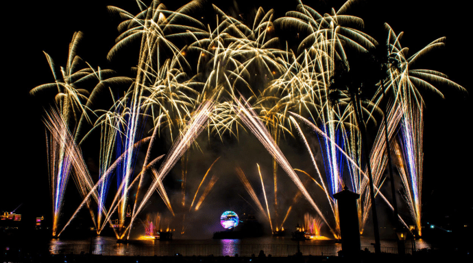 Gold and blue fireworks light up World Showcase Lagoon, highlighting fountains and the iconic globe during IllumiNations at EPCOT.