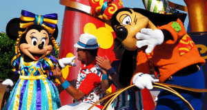 Minnie Mouse, Goofy, and a lively performer show off vibrant dance moves at Disney World’s energetic Move It Shake It parade.