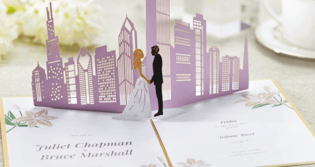Lovepop’s pop-up wedding invitation shows a city skyline with a bride and groom sharing a magical Disney Springs moment.