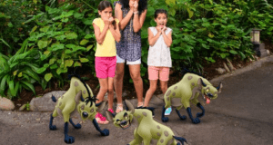 Guests at Animal Kingdom pose for a Magic Shot as Shenzi, Banzai, and Ed from The Lion King surround them on the path.
