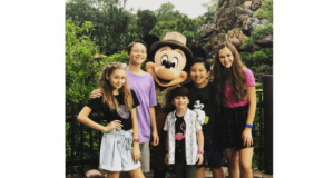 Five kids beam with excitement as they pose alongside Mickey Mouse at Walt Disney World, capturing a magical moment together.