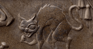 Stone carving of a fierce, hissing cat with arched back and bared teeth, setting a spooky mood for the Haunted Mansion queue.