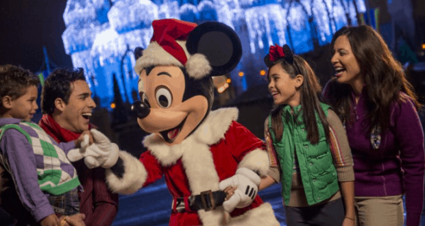 Guests pose with Mickey Mouse in a Santa suit before Cinderella Castle aglow with holiday lights at Disney World’s festive event.