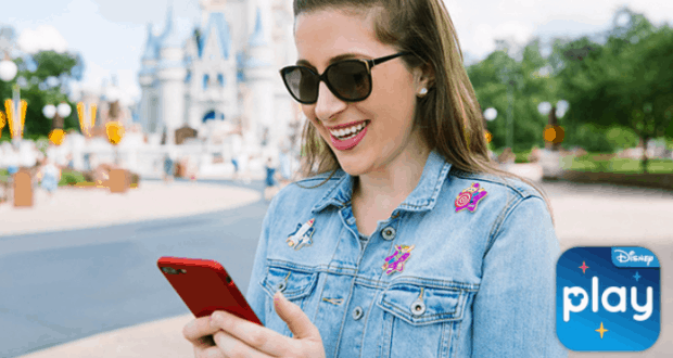 A guest in sunglasses smiles at her phone in front of Cinderella Castle, Play Disney Parks App logo ready to unlock Achievement Pins.