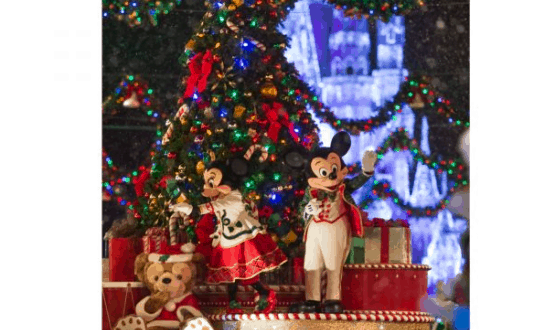 Mickey and Minnie, dressed in festive holiday outfits, greet guests by a glowing Christmas tree at Disney World’s Merry Christmas Party.