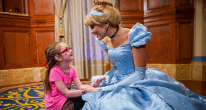 A young guest beams while holding hands with Cinderella in her signature blue gown, creating magical moments at Walt Disney World.