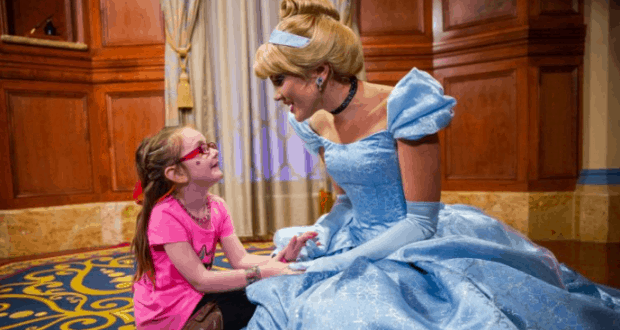 A young guest beams while holding hands with Cinderella in her signature blue gown, creating magical moments at Walt Disney World.