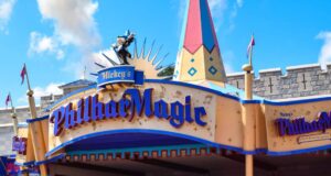 Entrance to Mickey’s PhilharMagic attraction at Disney, featuring a colorful sign with gold and blue lettering and a statue of Mickey Mouse in a sorcerer’s outfit holding a conductor’s baton on top.