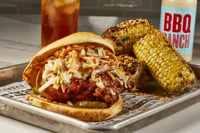 Savor a Polite Pig fried chicken sandwich meal at Disney World—coleslaw, grilled corn, iced tea, and BBQ ranch sauce included.