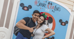 Guests beam with excitement in front of a Share Your Ears Disney backdrop, celebrating Disney’s Make-A-Wish donation—thumbs up!.