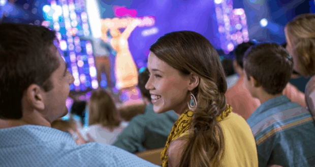 Guests seated at Epcot’s Festival of the Arts watch Disney on Broadway’s vibrant stage show, dazzled by colorful lights.