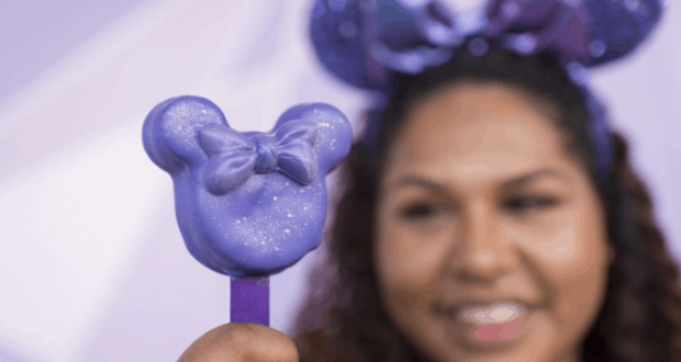 Minnie Mouse fan shows off a purple Minnie-shaped snack, complete with bow and matching ears, at Walt Disney World.