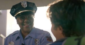 A smiling Disney World security officer in uniform talks to a child.