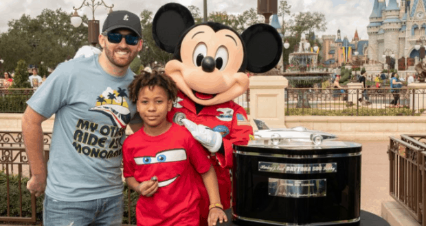 Mickey Mouse smiles with a man and child in front of Cinderella Castle at Walt Disney World, making magical memories together.
