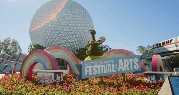 Epcot’s Festival of the Arts sign pops amid brilliant blooms, with Spaceship Earth shining in the background at Disney World.